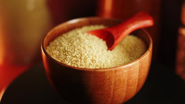 Explore uncooked couscous in a wooden bowl with a bright red spoon in a cozy kitchen setting