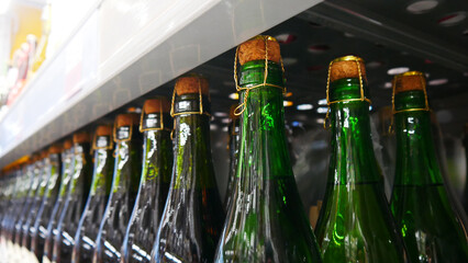 Close-up of many green glass wine bottles lined up on a retail display