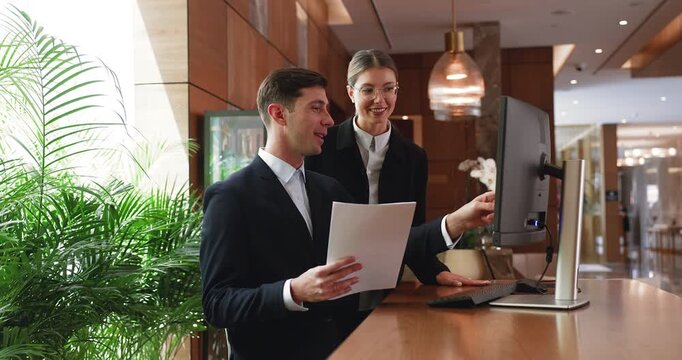 Two receptionists working together at hotel front desk
