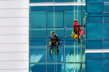 Workers, climbers wash windows of skyscraper.