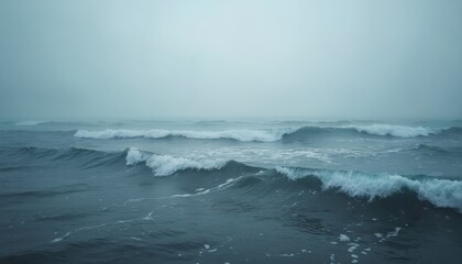 Fototapeta premium Calm ocean waves roll under dense fog. Misty seascape evokes serene atmosphere. Overcast weather at sea creates mood. Gray tones enhance natural beauty of waterscape. Perfect for zen theme