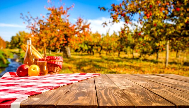 Wooden picnic table with red checkered cloth, apples, juice bottles, and basket; autumn orchard background