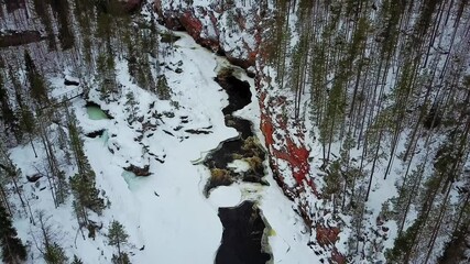 Aerial drone flight of cold canyon river and snow winter forest in Finland, Lapland - Powered by Adobe