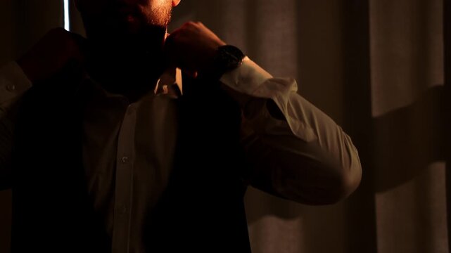 Close-up of a male businessman in a suit adjusting his shirt cuff. An elegantly dressed man adjusts his cufflinks. The groom adjusts the cufflinks on his shirt.