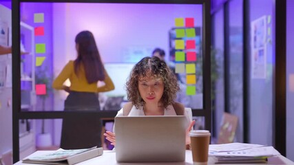 Creative Asian stylish woman having an online video call meeting with her client at night, presenting and suggesting her new business presentation idea confidently in a modern office atmosphere - Powered by Adobe
