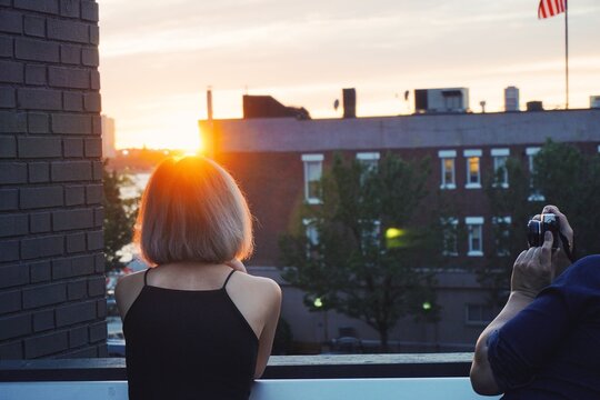 young couple taking golden hour sunset photo at high line in New York city, with sunset light peaking over head