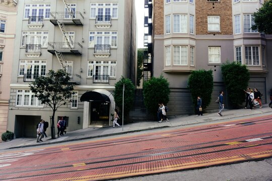 San Francisco street with people walking up and down the steep slopes, tram track in foreground