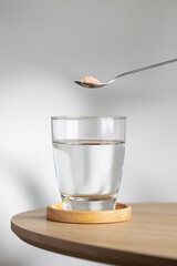 A spoon of Himalayan salt is being added to a glass of drinking water, highlighting its potential health benefits.