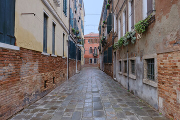 Quiet Venetian alleys with old brick facades, shuttered windows, and traces of daily life. The scene reflects the authentic atmosphere of Venice beyond its main tourist landmarks.