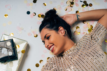 Woman celebrating holiday party with confetti and gifts
