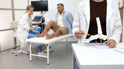 Anatomical model of foot bones on background of process of diagnostics of injured leg of patient by means of ultrasound scanning