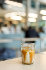 Cup of chilled milk dirty coffee on table by the window. Selective focus.