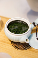 Closeup of fresh green tea leaves in tea pot.