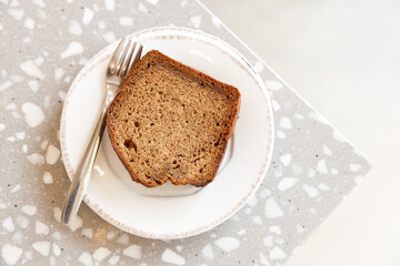 Moist Peanut butter Banana bread sliced with sauce on ceramic plate by the window.
