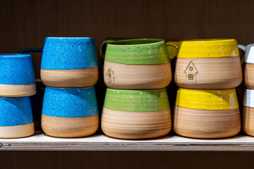 Colorful handmade ceramic mugs on shelf