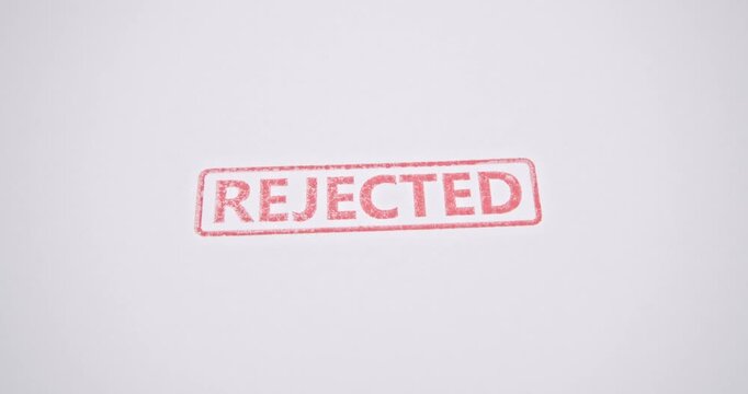 Close-up of REJECTED stamp in red ink on white paper, representing official denial, document rejection, or failed business approval.