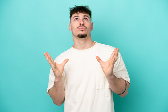 Young caucasian handsome man isolated on blue background stressed overwhelmed