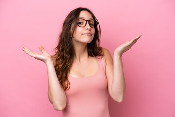 Young caucasian woman isolated on pink background making doubts gesture