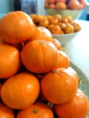 Fresh bright oranges neatly arranged on shelf in fruit market illuminated by warm light
