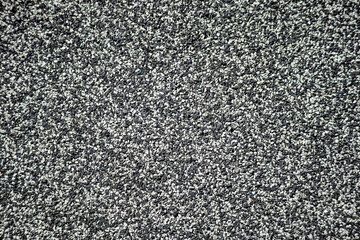 Closeup of black and white rubber granule surface used on playgrounds. Eco-friendly, shock-absorbing flooring for children’s safety.