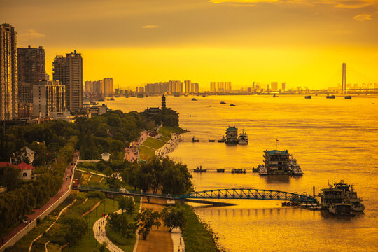 The Yangtze River and its shipping vessels, bathed in the glow of the setting sun, are located in Jiujiang, a historical and cultural ancient city in eastern Asia, Jiangxi Province, China.