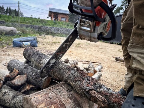 A man cutting a log into firewood using a chainsaw