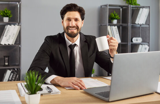 Businessman, smling man sitting at desk, holding white mug, smiling brightly, confident and relaxed, enjoying coffee break after working, contentment and professionalism, modern office setting - Powered by Adobe