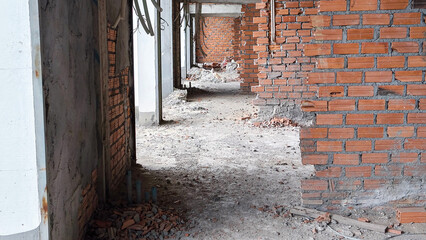 Hallway inside building under construction, with brick walls and rough flooring