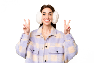 Young caucasian woman wearing winter muffs over isolated chroma key background showing victory sign with both hands