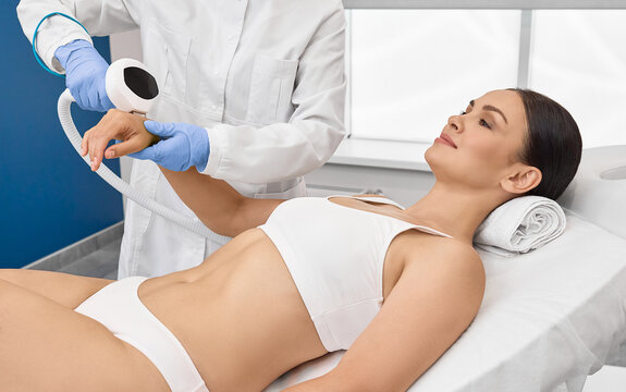 Fototapeta Photorejuvenation of woman arms using intense pulsed light IPL with beautician in cosmetology salon for rosacea treatment, removing brown spots and vascular mesh