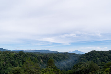 Scenic view of rolling hills and distant mountains under a blue sky, captured from Panorama Baru in Bukittinggi, West Sumatra.