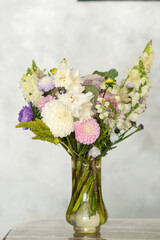 Elegant floral arrangement in glass vase with diverse colorful blooms on light background. Teacher's Day in Uzbekistan
