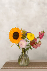 Colorful floral arrangement with sunflower, dahlia, and marigold in glass vase. Teacher's Day in Uzbekistan