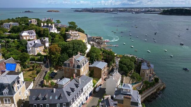 Dinard coastline, Rance estuary, with walled city of Saint-Malo in background, boats and villas, France. Aerial forward