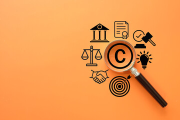 Fototapeta premium Copyright and intellectual property law concept. A magnifying glass focuses on the copyright symbol surrounded by icons of justice, contracts, and patents for the legal protection of creative work.