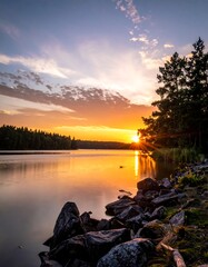 Fototapeta premium Sunset over a calm lake with trees and rocks