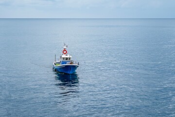 Obraz premium Blue Fishing Boat on Calm Sea, Small Vessel in Ocean, Commercial Fishing, Maritime Industry, Nautical Scene, Ocean, Fishing Industry, Navigation