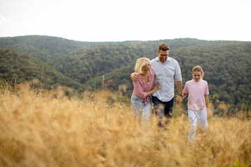 Family enjoying a sunny day in a grassy field near rolling hills with a peaceful landscape in autumn