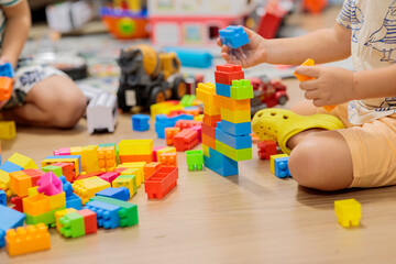 child playing with blocks.  Close-up of children's hands building tall tower with colorful wooden blocks on floor