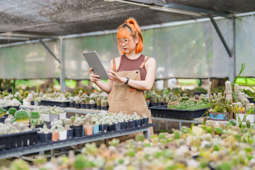 Young Asian Woman Tending to Cactus Plants with Care at a Sustainable Eco-Friendly Cactus Farm,...