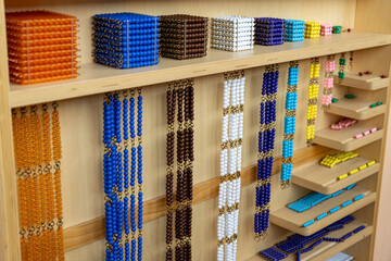 Development of mathematical skills according to the Montessori method. Multicolored cubes and beads on a shelf for alternative for studying mathematics in elementary or primary school 