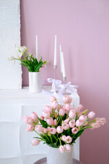 Elegant floral arrangement featuring pink tulips and white candles in minimalist vases against a soft pastel backdrop, creating a serene and inviting atmosphere for home decor