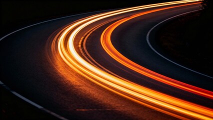 A dynamic light trail curves along a dark road at night, capturing the motion of vehicles in a long-exposure photograph.