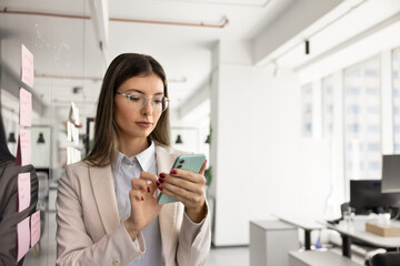 Serious busy project manager using online business application on smartphone