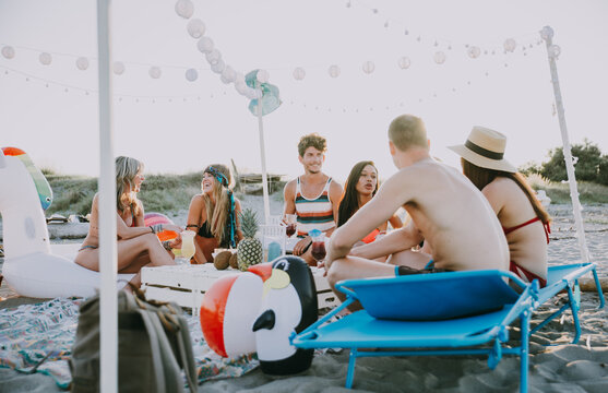 Group of friends making party on the beach at sunset time