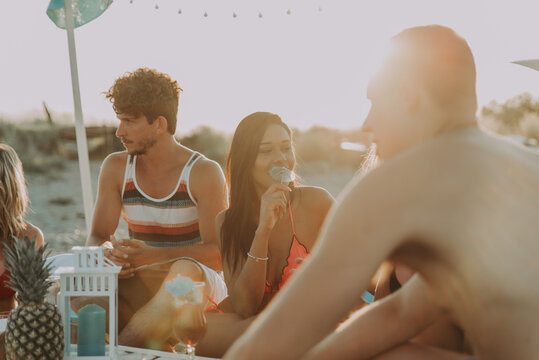 Group of friends making party on the beach at sunset time