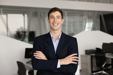 Positive young professional man posing on office with hands folded