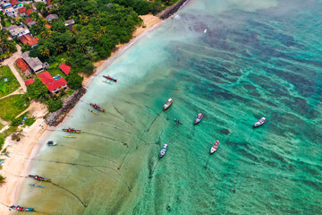 Traditional catamarans and fishing boats on Weligama Beach, Sri Lanka—drone shot of ocean, palms, and local culture
