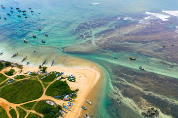 Traditional catamarans and fishing boats on Weligama Beach, Sri Lanka—drone shot of ocean, palms, and local culture