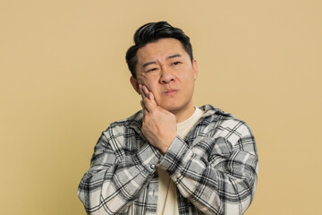 Dental problems. Asian middle-aged man touching cheek, closing eyes with expression of terrible...